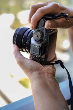 Photographer doing photos with still camera. Mirrorless camera in the hands of tourist taking photos of a city isolated on white background with copy space for text. Learning photography concept
