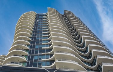 A highrise building against the blue sky. Condominium or apartment building. Looking Up Modern Building. Architecture details Modern Building Glass facade-Surrey Canada-January 10,2023