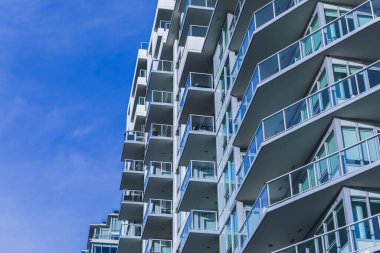 Modern apartment buildings on a sunny day with a blue sky. Facade of a modern apartment building with balconies. Multistoried new stylish living block of flats. nobody, selective focus, copy space