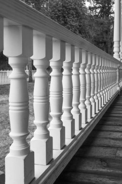 Wooden walkout deck with white railings outdoor in a beautiful garden. Wooden deck of a house with white railings. Nobody, street photo, selective focus