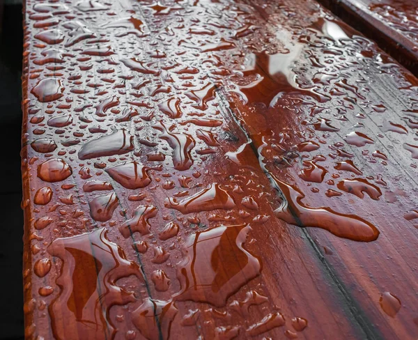 Surface in drops after rain. Droplet of water on wood and sunlight after rain. Abstract pattern of water droplets on a brown wooden surface. Nobody