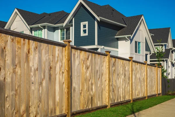 Nice wooden fence around house. Wooden fence with green lawn.Nice wooden fence around house. Wooden fence with green lawn. Street photo, nobody, selective focus