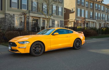 Yellow muscle car Ford Mustang at the countryside. Front headlights of yellow modern car on a street. Nobody, street photo, editorial-January 30,2023-Surrey Canada