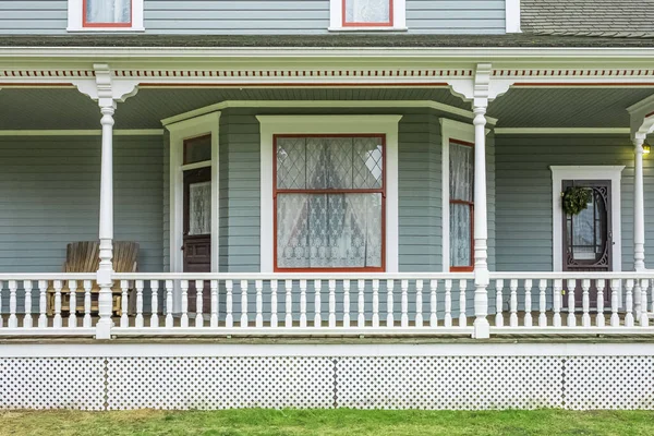 House with porch and white railings. White veranda and railing posts, brown boards, elevated above ground. Wooden deck of a house with white railings. Nobody, street photo, selective focus
