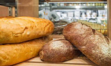 Freshly baked bread on shelfs. Baked products at a supermarket. Healthy and nutritious food. Bread making business. Different fresh bread on the shelves in bakery.