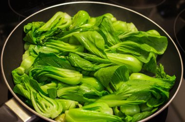 Bok choy stir fry on pan. Stir fried vegetables in a chinese wok. Stalks of baby bok choy cooking on the pan. Nobody, selective focus