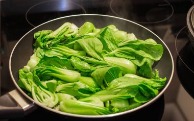 Bok choy stir fry on pan. Stir fried vegetables in a chinese wok. Stalks of baby bok choy cooking on the pan. Nobody, selective focus