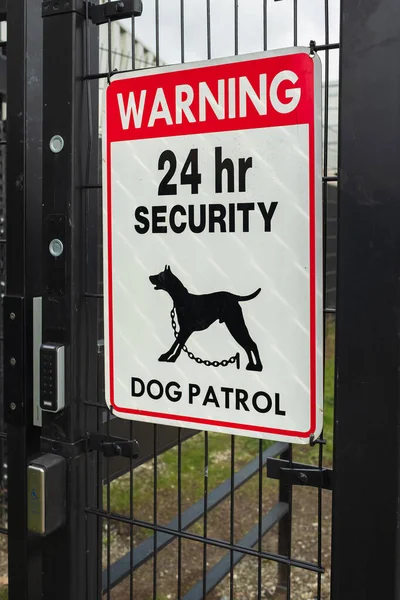 Security patrol sign with guard dog. Warning Guard Dogs On Duty Text Sign on a gate. 24 hours security dog patrol warning sign. Nobody, street photo, selective focus