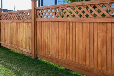 Nice new wooden fence around house. Wooden fence with green lawn. Street photo, nobody, selective focus