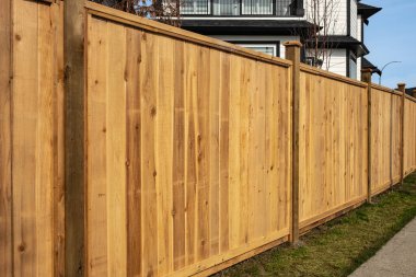 Nice new wooden fence around house. Wooden fence with green lawn. Street photo, nobody, selective focus