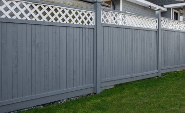 Nice new wooden fence around house. Wooden fence with green lawn. Street photo, nobody, selective focus