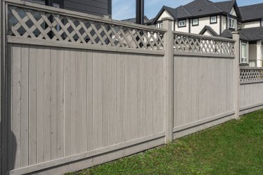 Nice new wooden fence around house. Wooden fence with green lawn. Street photo, nobody, selective focus