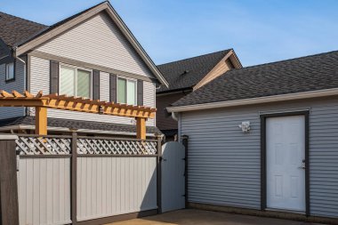 Banliyödeki evinin kapısı gri çitli, modern müstakil katlı bir ev. Evin arkasındaki ahşap kapı ve çit. Sokak fotoğrafı, kimse yok.