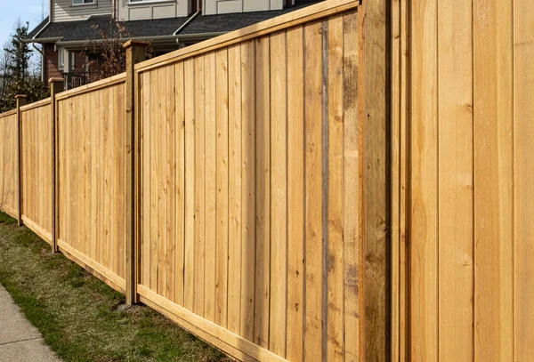 Nice new wooden fence around house. Wooden fence with green lawn. Street photo, nobody, selective focus