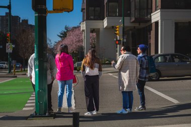Vancouver Kanada 'nın modern mimari alanında yeşil ışık bekleyen insanlar. Trafik ışıklarında, yaya geçidinde bekleyen bir grup insan. Sokak fotoğrafı... 22 Mart 2023.