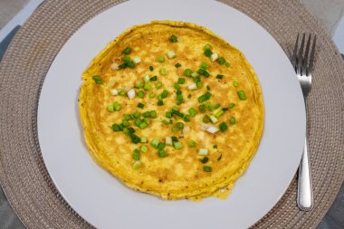 Simple egg omelette with herbs on white plate. Fluffy breakfast omelette with green spring onions. Breakfast with pan-fried eggs. Keto ketogenic diet. Texture of omelet. Nobody, selective focus clipart