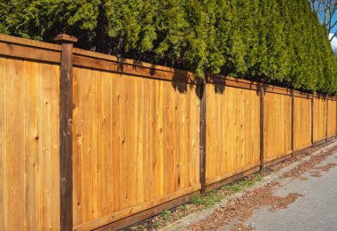 Nice new wooden fence around house. Wooden fence with green lawn. Street photo, nobody, selective focus