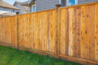 Nice new wooden fence around house. Wooden fence with green lawn. Street photo, nobody, selective focus