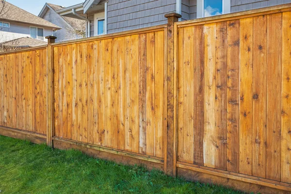 Nice new wooden fence around house. Wooden fence with green lawn. Street photo, nobody, selective focus
