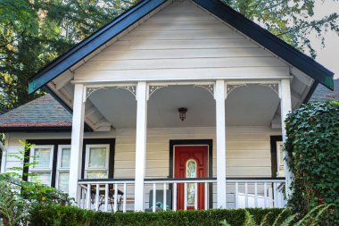 Kırmızı kapılı Amerikan evinin ön sundurması. Giriş verandası olan küçük eski bir ev. Emlak Harici Cephe Evi. Hiç kimse, seçici odak, sokak fotoğrafı.