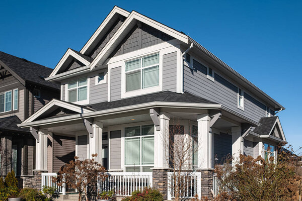 Real Estate Exterior Front House on a sunny day. Big custom made luxury house with nicely landscaped front yard in the suburbs of Vancouver Canada in springtime. Street photo, nobody