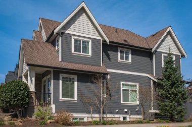 Güneşli bir günde gayrimenkul paravanı. Baharda Vancouver Kanada 'nın banliyölerinde manzaralı ön bahçesi olan büyük lüks bir ev.