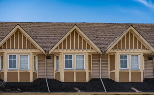 Houses in suburb in the north America. Top of a house with nice windows over blue sky. Beautiful Home Exterior. Real Estate Exterior Front House. Nobody. Roof shingles on top of the house
