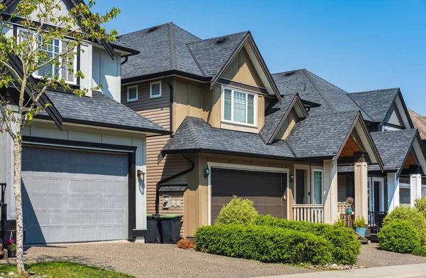 A perfect neighborhood. Houses in suburb at Spring in the north America. Real Estate Exterior Front Houses on sunny day. Big custom houses with nicely landscaped front yard-British Columbia Canada