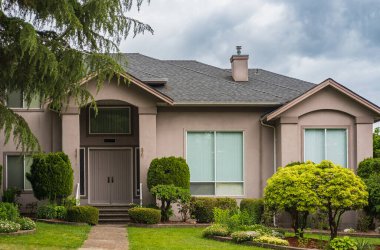 Güneşli bir günde gayrimenkul paravanı. Vancouver Kanada 'nın banliyölerinde baharda bahçeli lüks bir ev. Bahçeli güzel bir ev.