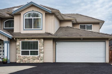 Güneşli bir günde gayrimenkul paravanı. Vancouver Kanada 'nın banliyölerinde bahçe ve garaj yolu güzel döşenmiş lüks bir ev.