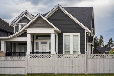 Güneşli bir günde gayrimenkul paravanı. Vancouver Kanada 'nın banliyölerinde baharda ön bahçesi ve çiti olan büyük lüks bir ev. Bahçeli güzel bir ev.