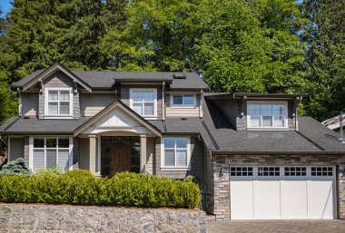 Güneşli bir günde gayrimenkul paravanı. Bahçe bahçesi güzel döşenmiş lüks bir ev ve yazları banliyöde garajdan garaja. Bahçeli güzel bir ev girişi.