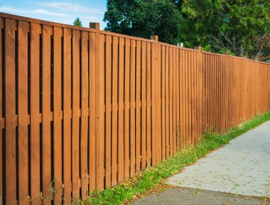 Nice new wooden fence around house. Wooden fence with green lawn. Street photo, nobody, selective focus