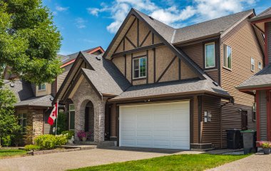 Güneşli bir günde gayrimenkul paravanı. Yazın banliyölerde bahçe ve garaj yolu güzel döşenmiş lüks evler. Bahçeli güzel bir ev girişi.