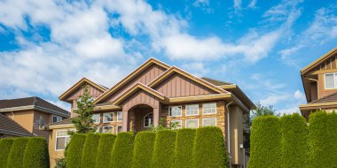 Güneşli bir günde gayrimenkul paravanı. Yazın banliyöde manzarası güzel olan büyük lüks bir ev. Bahçesi ve ağaçları olan güzel bir ev girişi.