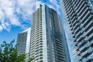 Arka planda mavi gökyüzü ve balkonları olan yeni apartmanlar. Surrey BC apartmanının manzarası. Yüksek katlı konut binasının dışı. Banliyö bölgesinde yeni bir apartman.
