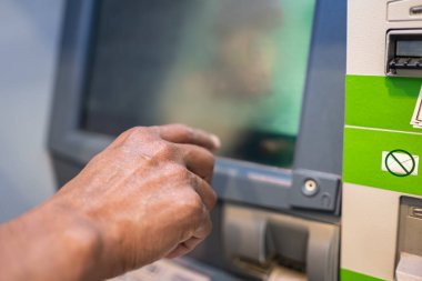 ATM 'de ve banka makinesinde yazarken akıllı telefon kullanan erkeklerin yakın çekimleri. ATM 'den bir adamın eli ekrana geliyor. Finansal sistem. Modern teknolojiler. Kredi kartıyla ATM kullanan bir adam.