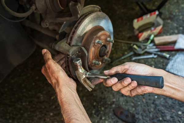 Car disk brake pad replacement service by hand of mechanic man. Auto mechanic repairing the breaks of a car, disc brake without wheels of the vehicle for repair. Replacing brake pads