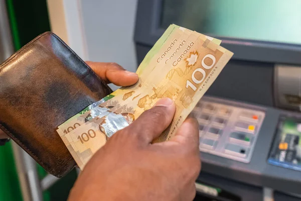 Cash withdrawal at an ATM. Money in the hands of close-up. Canadian dollars banknotes and cash machine. Money in hands. Man\'s hand withdrawing cash. Finance customer and banking service concept