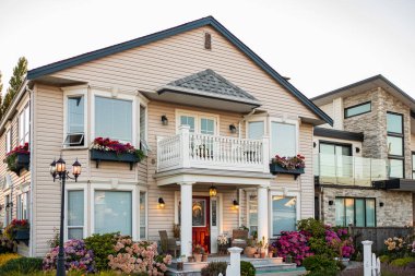 Yazın bahçesinde manzarası güzel olan büyük, modern, lüks bir ev. Güzel bahçeli güzel bir ev girişi. Kapıdaki saksılarda çiçekler ve bitkiler bir eve açılıyor.