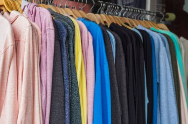 Çok renkli kapüşonlu kazak mağazada asılı duruyor. Farklı renklerde kaşmir kazaklar ve kapüşonlular, elbise askısındaki sweatshirtler. Elbise mağazasında askılarda kapüşonlular