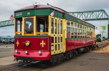 Astoria Riverfront Trolley with tourists on a tour in town Astoria USA on old freight railroad tracks near the Columbia River.Trolley rides under the Astoria-Megler bridge on a riverside-August 6,2023 clipart