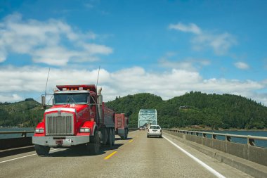 Otoyolda römork kullanan kırmızı kamyonet. Kargo taşıyan büyük bir sanayi kamyonu. İş, ticari, kargo taşımacılığı kavramı - 7 Ağustos 2023-Astoria USA