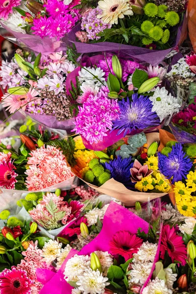 Flowers are near a flower shop on a city street. Beautiful bouquets of various flowers are presented in a flower shop. Bouquets on table, florist business. Different varieties fresh spring flowers