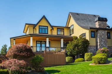 Güneşli bir günde gayrimenkul paravanı. Yazın bahçesinde manzarası güzel olan büyük, modern, lüks bir ev. Bahçeli güzel bir ev girişi. Mükemmel bir mahalle.