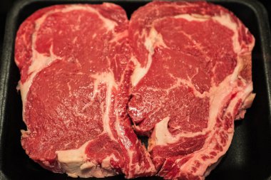 Biftek. Siyah arka planda taze çiğ biftek, üst manzara. Köpük tepside çiğ kaburga bifteği. Mermer biftek, çiğ et. Hiç kimse, seçici odaklanma