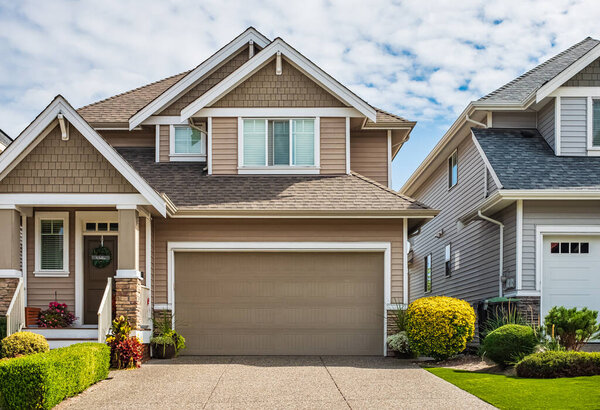 Real Estate Exterior Front House on a sunny day. Big custom made luxury house with nicely landscaped front yard and driveway to garage in suburbs. Modern designed home, New construction home exterior