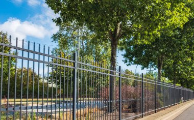 Otoyoldaki trafik engeli, araçları kazadan korumak. Cadde boyunca uzun ve uzun demir çitler var. Karayolu ile. Çit şehirde.