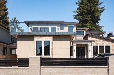 Güneşli bir günde gayrimenkul paravanı. Bahçesi güzel döşenmiş lüks bir ev ve banliyödeki garajdan garaja giden bir yol. Modern tasarım ev, yeni inşaat evi dış görünüş