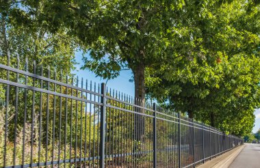 Otoyoldaki trafik engeli, araçları kazadan korumak. Cadde boyunca uzun ve uzun demir çitler var. Karayolu ile. Çit şehirde. Metal siyah çit, baraj sokağı.